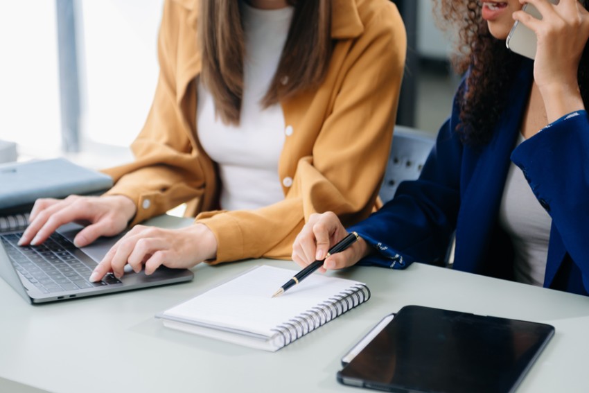Two women working with a laptop and a notebook