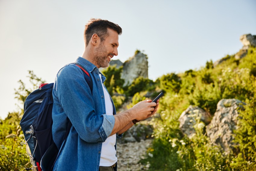 Man with backpack on mobile phone outdoors