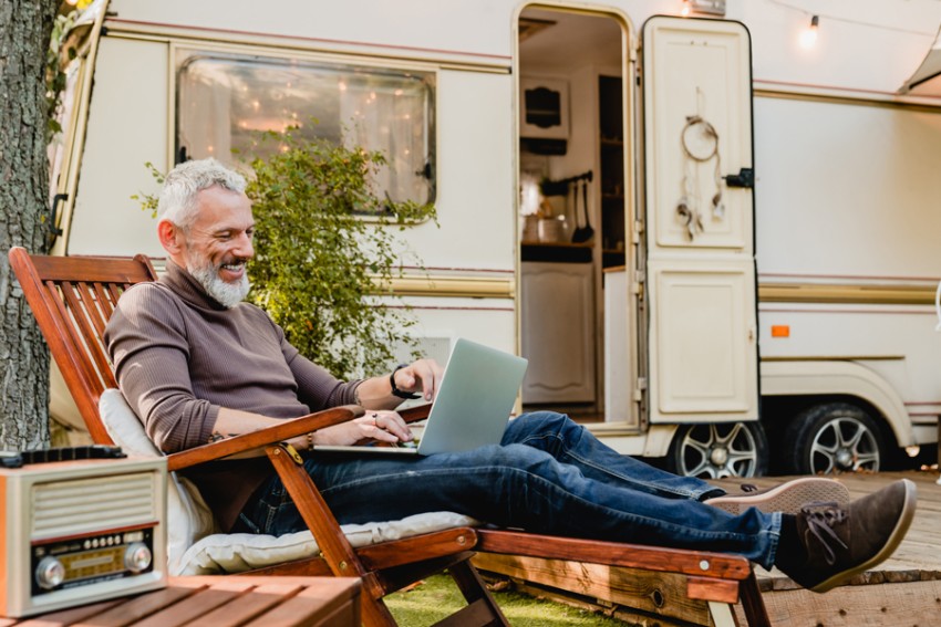 man sitting with laptop in front of an RV